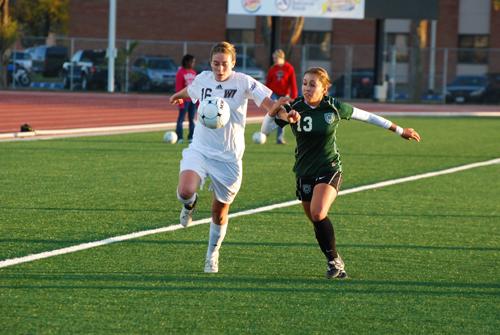 Heather Hollis races an ENMU player to the ball. Photo by Melissa Bauer-Herzog.
