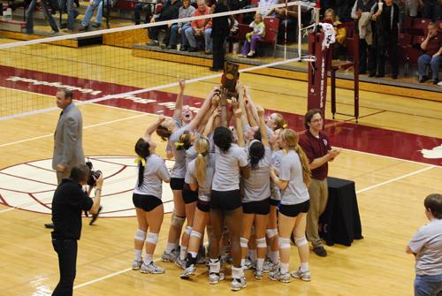 The volleyball team celebrates after their sweep of the conference tournament. Photo by Melissa Bauer-Herzog.