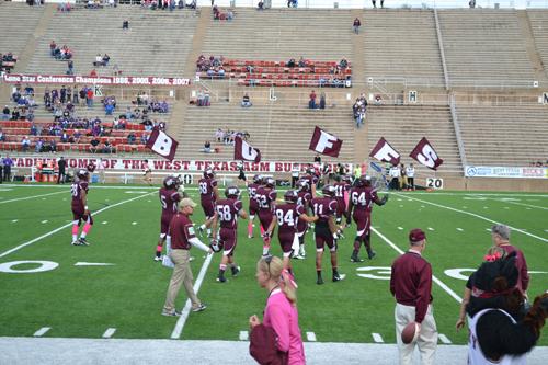 Maroon Platoon charge the field with flags as the football players enter. Photo by Alex Montoya.