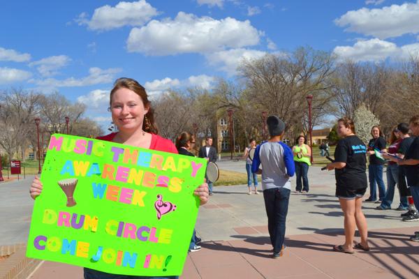 Vice President Meghan Garner holds up a sign to invite people to join Music Therapy Awareness Week.