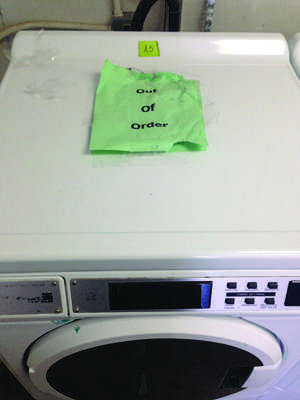 An out of order sign on one of the washing machines.