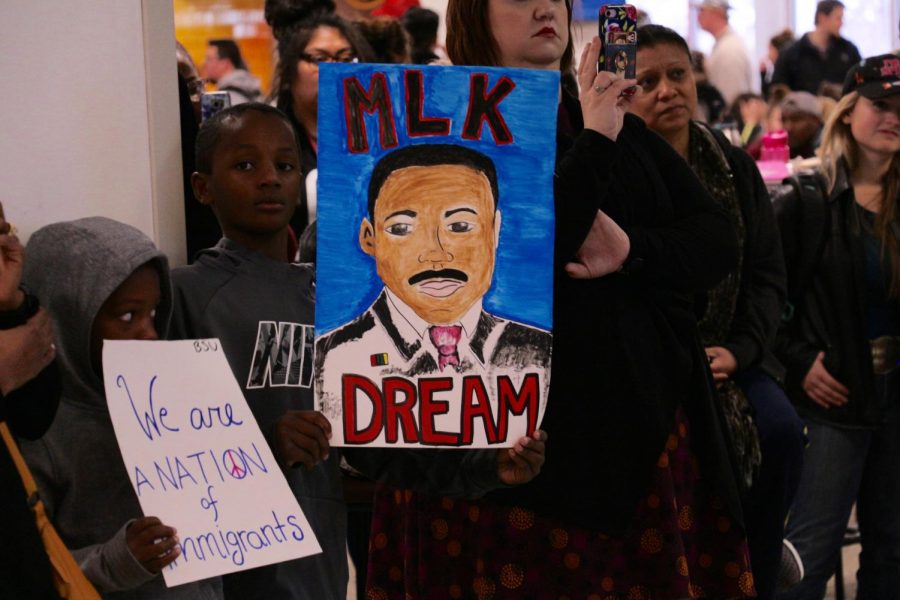 Julian Reese Jr. holds a sign depicting Martin Luther King Jr. as the crowd takes in the speech.