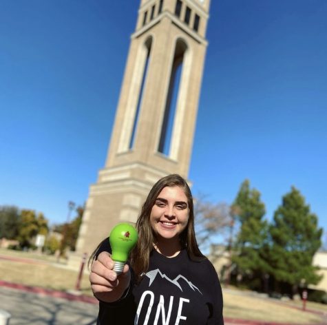 Ustina Guirguis advertising Greenlighting for Advising Services by holding a green bulb at the WTAMU clock tower. 