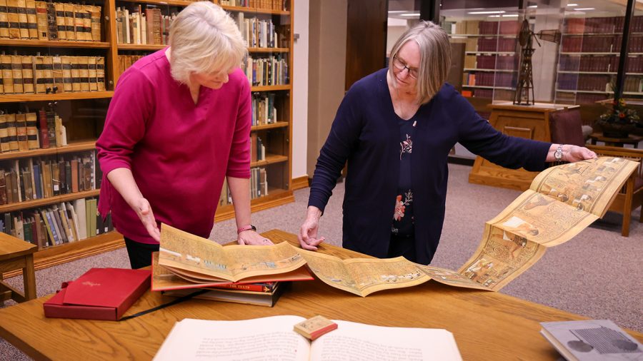 Librarians Lisa Insall and Sidnye Johnson look over a copy of the Egyptian Book of the Dead published for the Limited Editions Club, part of a donation to Cornette Library and the Texas Poets Corner. Photo provided by WT Communication and Marketing