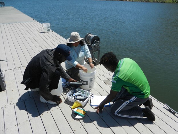 From left, Simon Mbanefo, a graduate student in environmental science, Heather Ogle, a junior environmental science major and Afolarin Olatunbosun, a graduate student in environmental science, collect water from Lake Meredith as part of research looking into microorganisms and water quality in the lake.
